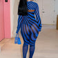 Woman in a blue and black striped outfit by Gsuwoo walking in a hallway.
