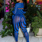 Person in a blue and black striped outfit by Gsuwoo standing among potted plants indoors.
