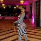 Woman in a black and grey striped outfit by Gsuwoo standing in a stylish interior setting with chandeliers and pink lighting.