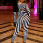 Woman in a black and grey striped outfit by Gsuwoo standing in a stylishly decorated room with pink lighting.