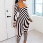 Woman wearing a black and nude striped outfit by Gsuwoo in a modern room with large windows.