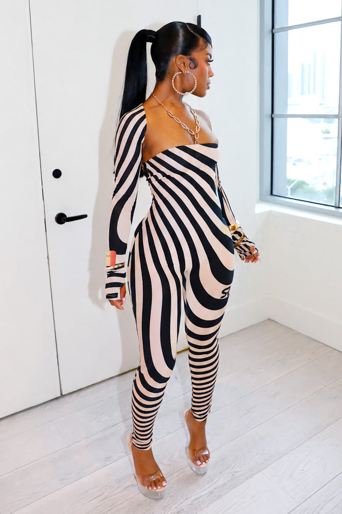 Woman wearing a black and nude striped outfit by Gsuwoo in a modern room with large windows.